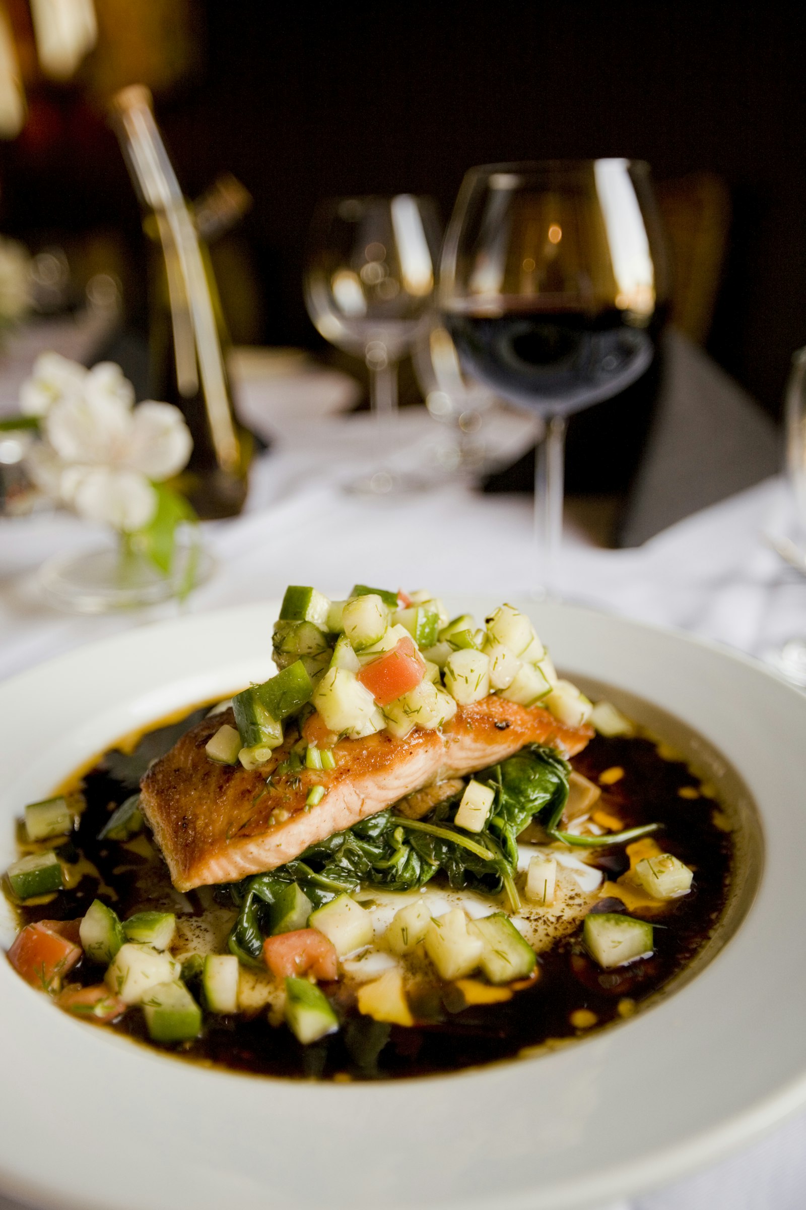 Plated salmon dinner with a glass of wine on a set table